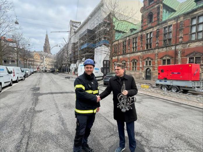 Brian Mikkelsen får overrakt den genfundne del af fløjstangen af en vagtmester ved Børsen. 