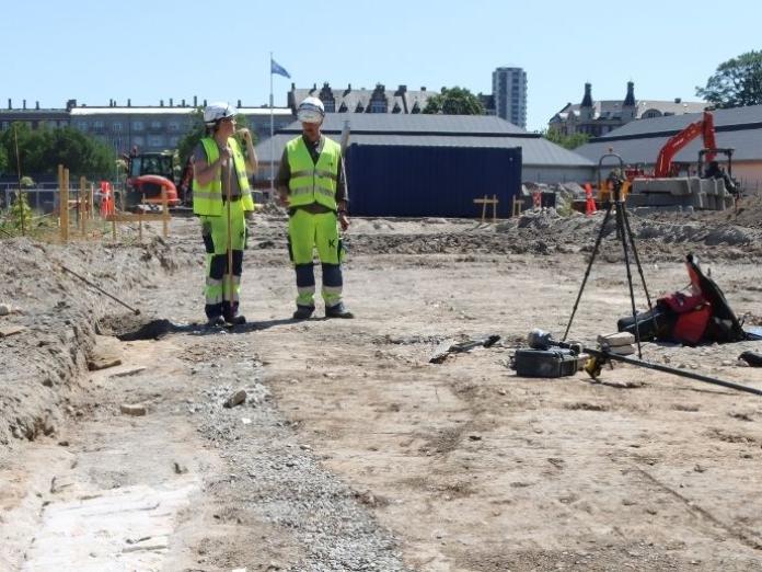 Arkæologer i gult tøj i felt