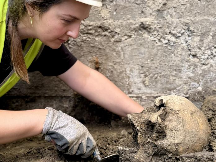 Arkæolog fra Københavns Museum i gang med at udgrave et skeletkranium fra jorden 