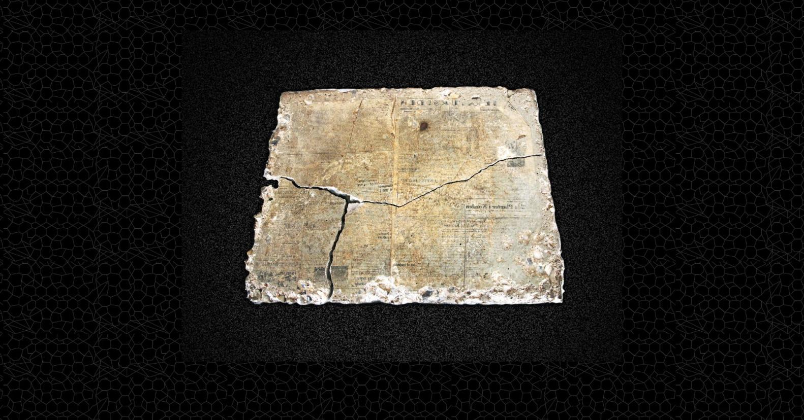 Fragment af cementflise med aftryk af avis